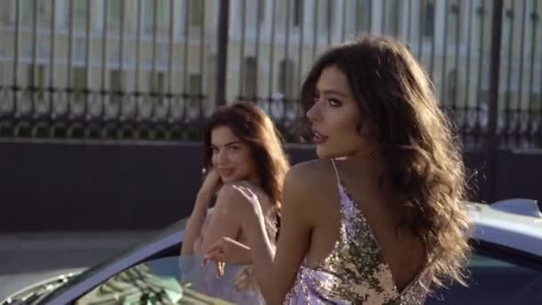 Dos mujeres jóvenes posando cerca de coches deportivos de lujo — Vídeo de stock