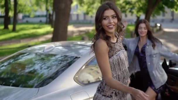 Dos mujeres jóvenes posando cerca de coches deportivos de lujo — Vídeo de stock