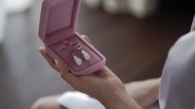 Genç kadın pembe kutu ve giyen küpe alır
