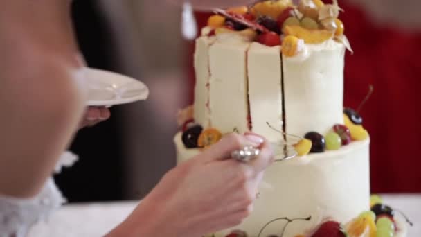 Невеста и грим резки куски белого торта торт с фруктами на вечеринке — стоковое видео