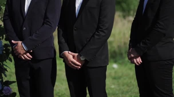 Tre män i svarta klassiska kostymer vistas utomhus — Stockvideo