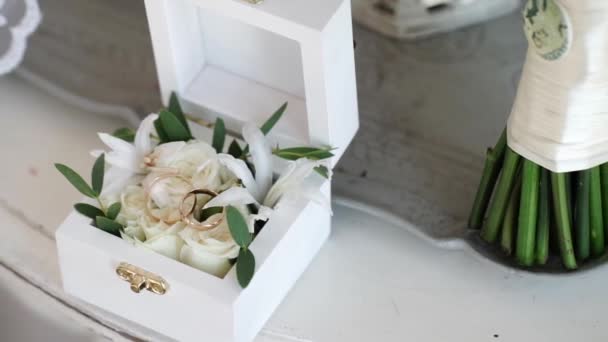 バラの花と白い木製の箱に 2 つの黄金結婚指輪 — ストック動画