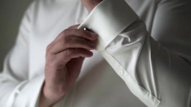 Kol düğmeleri üzerinde koymak beyaz tişörtlü genç adam