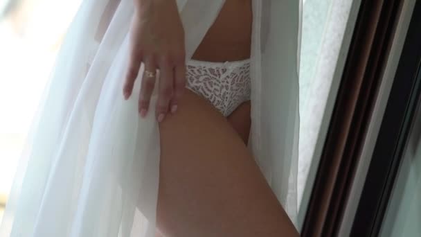 Joven mujer fuerte en lencería blanca posando cerca de la ventana y agitando su vestido bodouir — Vídeos de Stock