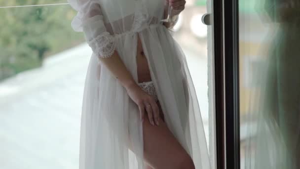 Ung stark kvinna i vita underkläder poserar nära fönster och vinka hennes bodouir klänning — Stockvideo