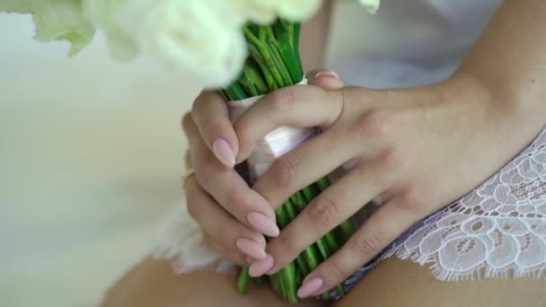 Joven mujer fuerte en lencería blanca sentada en la cama con ramo de novia con rosas blancas — Vídeos de Stock