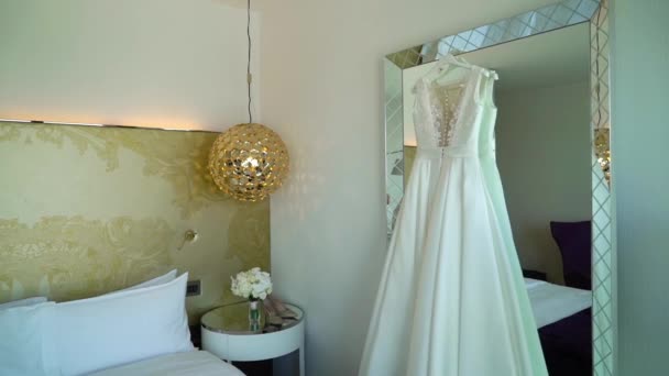 Gaun pernikahan di cermin di kamar tidur hotel mewah. Bridal buket dari mawar putih . — Stok Video