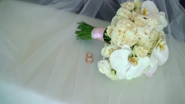 Bridal wedding bouquet of white roses on veil and two wedding rings — Stock Video
