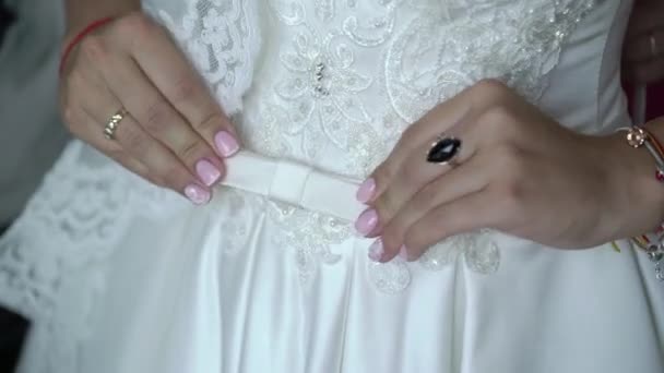 Молодая невеста прикрепляет пояс к свадебному платью — стоковое видео