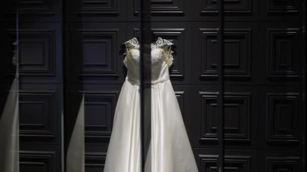 White wedding bridal dress on dark wall with reflections in mirrors — Stock Video