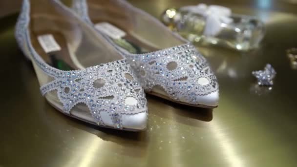 Zapatos de novia con pastas y pendientes de joyería sobre fondo dorado — Vídeo de stock