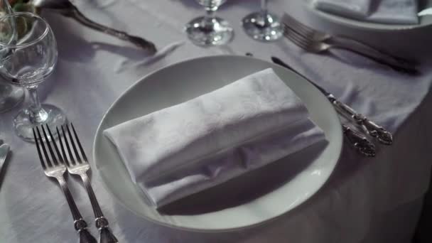 Placa, guardanapo de pano, faca e garfo em pano branco na mesa no restaurante — Vídeo de Stock