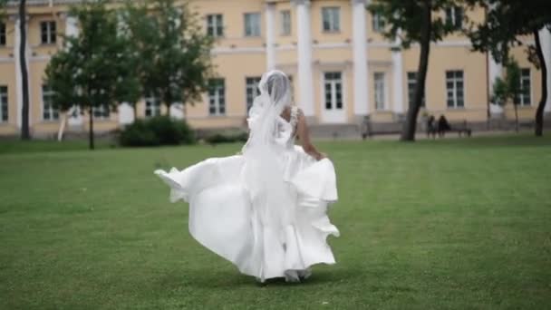 Ung brud kör i en park slowmotion viftande klänning på mulen dag — Stockvideo