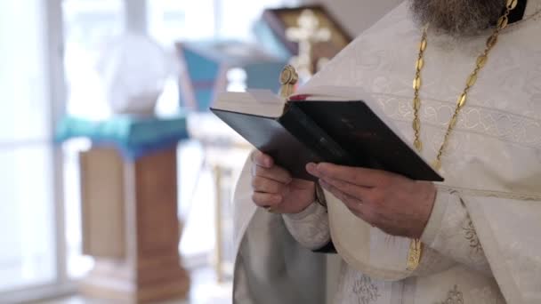 Priester bidden met boek van de Bijbel in de kerk — Stockvideo