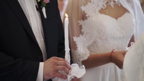 Bruden och brudgummen håller ljus i kyrkan vid ceremoni — Stockvideo