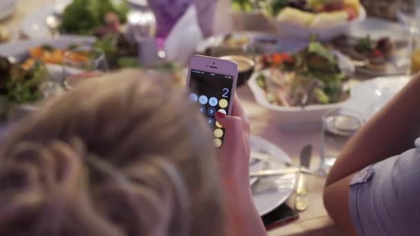 Mulher com calculadora no telefone monile na contagem do restaurante — Vídeo de Stock