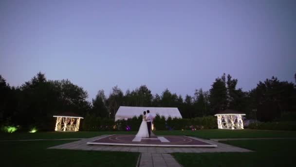 Bride and groom staying at helicopter landing base, embracing at the evening — Stock Video