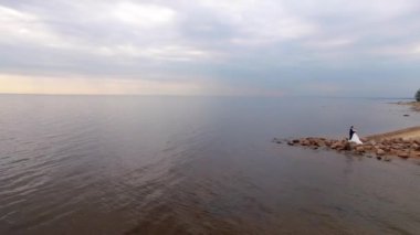 Gelin ve damat kalan ve deniz kenarında kumlu plaj kayalar, yaz sarılma.