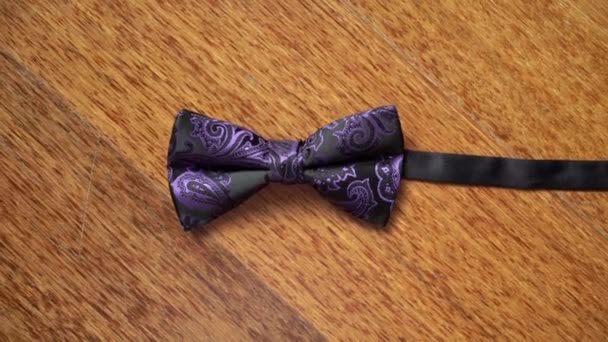 Фиолетовый галстук-бабочка на деревянном столе — стоковое видео