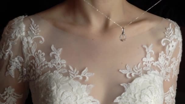 Boda. Joyas. La novia en un vestido blanco poniéndose un collar alrededor de su cuello — Vídeo de stock