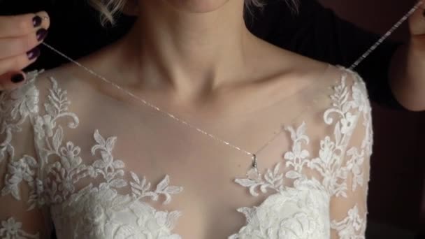 Свадьба. Драгоценности. Невеста в белом платье надевает ожерелье на шею — стоковое видео