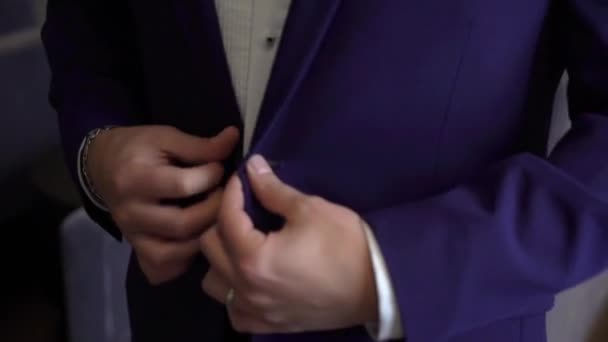 Vista ravvicinata delle mani dello sposo che abbottona la giacca nuziale . — Video Stock
