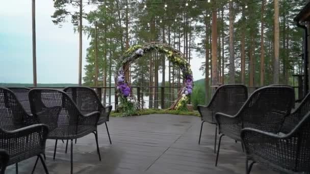Bruiloft. De ceremonie van het huwelijk. Boog, versierd met paarse en gele bloemen staan in het bos, op het gebied van huwelijk ceremonie — Stockvideo