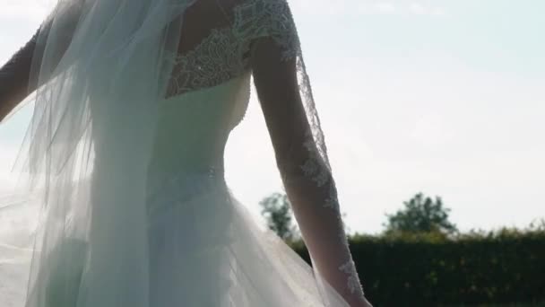 Jeune mariée femme en robe de mariée magnifique avec agitant tissu volant, mode femelle posant dans le parc 