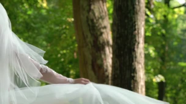 Jeune mariée femme en robe de mariée magnifique avec agitant tissu volant, mode femelle posant dans le parc — Video