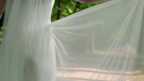 Jeune mariée femme en robe de mariée magnifique avec agitant tissu volant, mode femelle posant dans le parc — Video