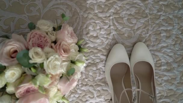 Brud-tillbehör: vita skor och brudar bukett med vita och rosa rosor på en säng — Stockvideo