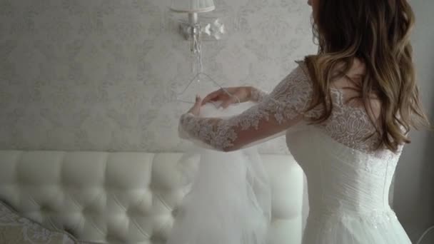 Young beautiful bride in dress takes veil in bedroom — Stock Video