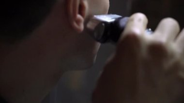 Aşırı yakışıklı genç bir adam elektrikli ustura ile tıraş yakın