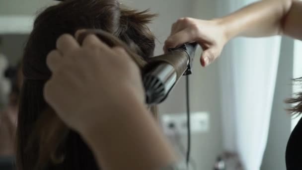 Peluquero haciendo rizos en el cabello del cliente usando rizador eléctrico — Vídeo de stock