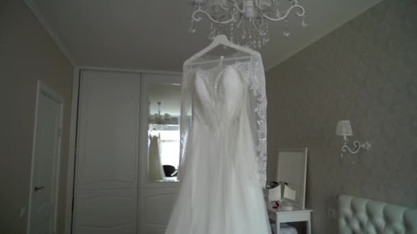 Vestido de novia de lujo colgando en el dormitorio. Silueta de increíbles novias vestido de encaje en la luz. Preparación matutina, preparándose — Vídeos de Stock