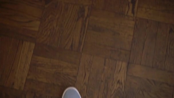 POV de pessoa. Ponto de vista do homem andando dentro de casa no chão de madeira em sapatos casuais esporte azul. ângulo de 90 graus de pessoa — Vídeo de Stock