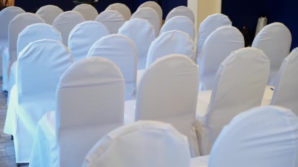 Silla con el lado posterior del paño de la cubierta blanca en una fila en un pasillo grande para la boda, conferencia o seminario — Vídeo de stock