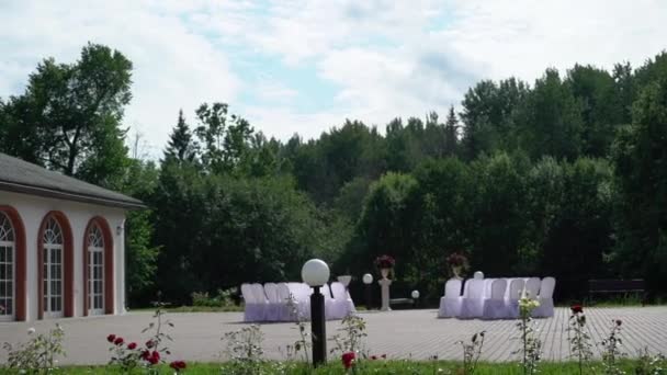 Hermosa decoración de la ceremonia de boda en el parque con estanque y edificio del palacio, lado del país . — Vídeo de stock
