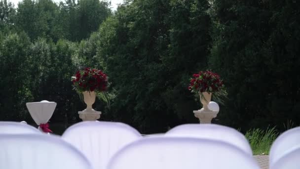 Hermosa decoración de la ceremonia de boda en el parque con estanque y edificio del palacio, lado del país . — Vídeo de stock