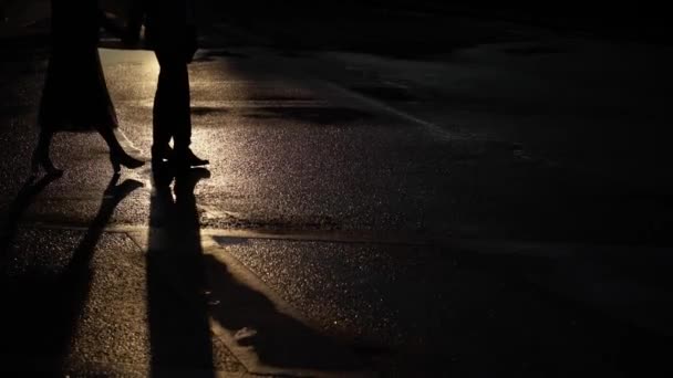 Mann und junge Frau gehen auf einer Straße. Pärchen, das sich am frühen Morgen auf einer Straße in der Stadt an den Händen hält, Schatten auf dem Boden — Stockvideo