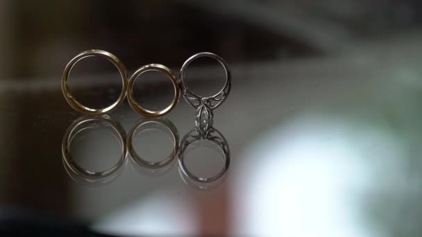 Wedding golden rings with diamond rolls on glass table — Stock Video