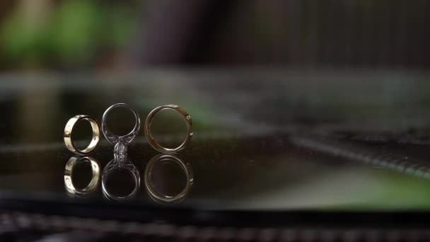 Gouden ringen met diamanten bruiloft rolt op glazen tafel — Stockvideo