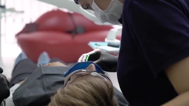 Дантист лечит зубы пациентке в клинике. Женщина профессиональный врач стоматолог на работе. Проверка зубов — стоковое видео