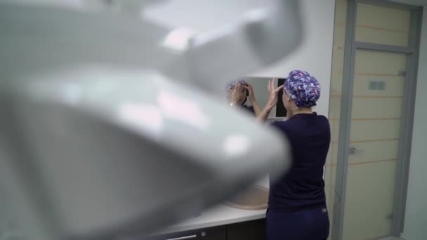 Ženský lékař nasadil masku. Mladá brunetka lékař nebo zdravotní sestra v modrém kabátě klade na obličejovou masku v nemocnici — Stock video