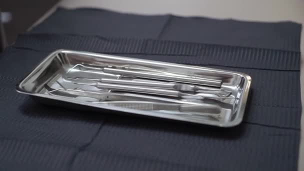 Dentysta biorąc instrumentu z zasobnika na stole — Wideo stockowe