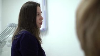 Diş hekimi ve hasta, arka planda tıbbi ekipmanlarla yapılan bir muayenede tedaviyi seçiyor