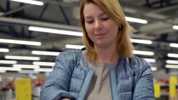 Mujer joven comprando en el hipermercado. Elegir zapatos en una tienda — Vídeos de Stock