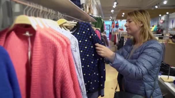 Mooie jonge vrouwen het kiezen van kleding in de winkel — Stockvideo