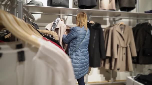 Jovens mulheres bonitas escolhendo roupas na loja — Vídeo de Stock