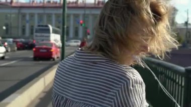 Gülümseyen ve bir şehirde poz sarışın genç kadın